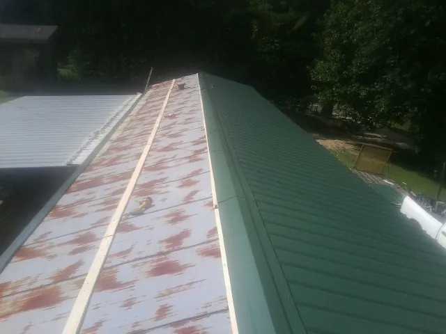Old rusted panels beside newly installed green metal roofing — Wind Damage Roof Repair by Roofing Brothers in Summerfield
