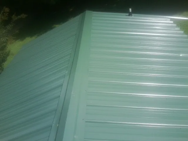 New green metal panels meeting at the ridge of a roof — Flat Roof Repair work by our crew in Summerfield