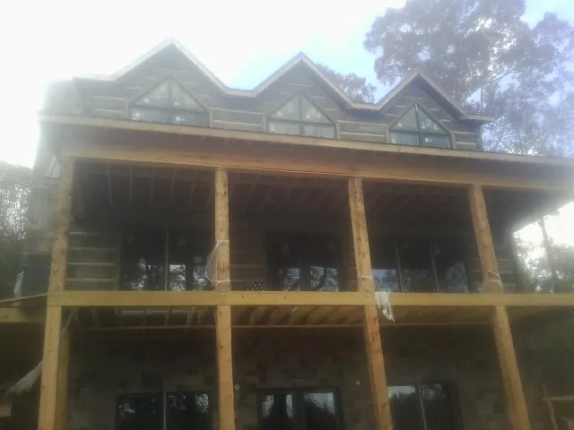 Dormers and porch framing on a large log home under construction — Roof Coating work by our crew in Summerfield