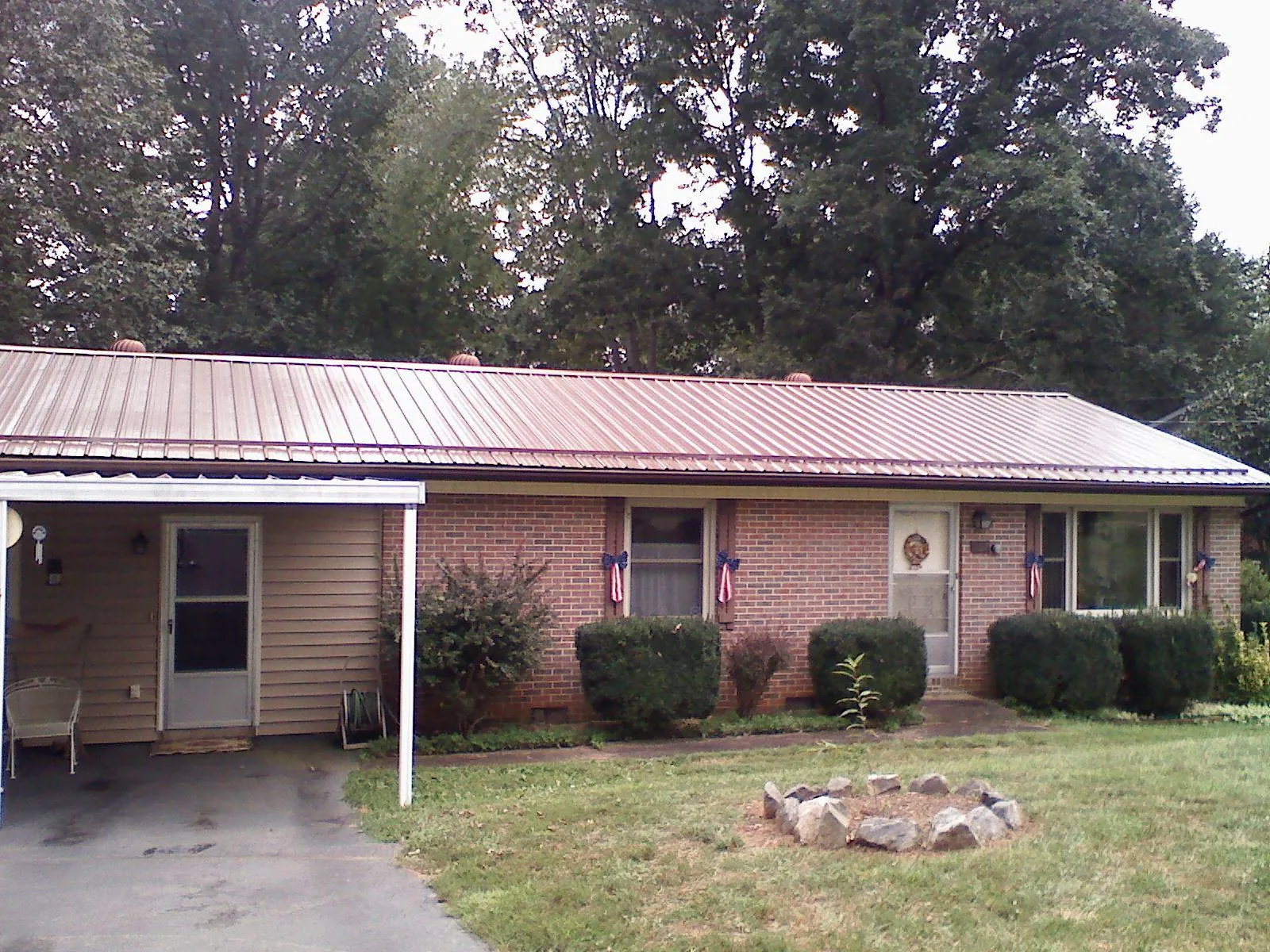 Bronze metal roof and carport on a brick ranch home — Roof Repair work by our crew in Summerfield