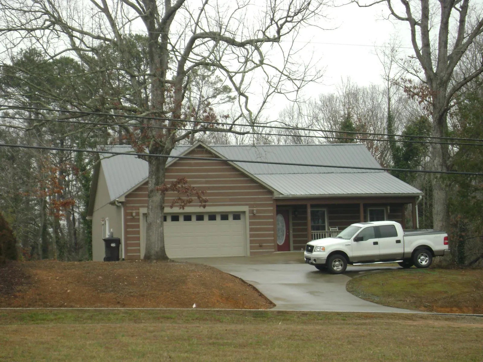 Gray metal roof on a log sided house with an attached two car garage in Summerfield