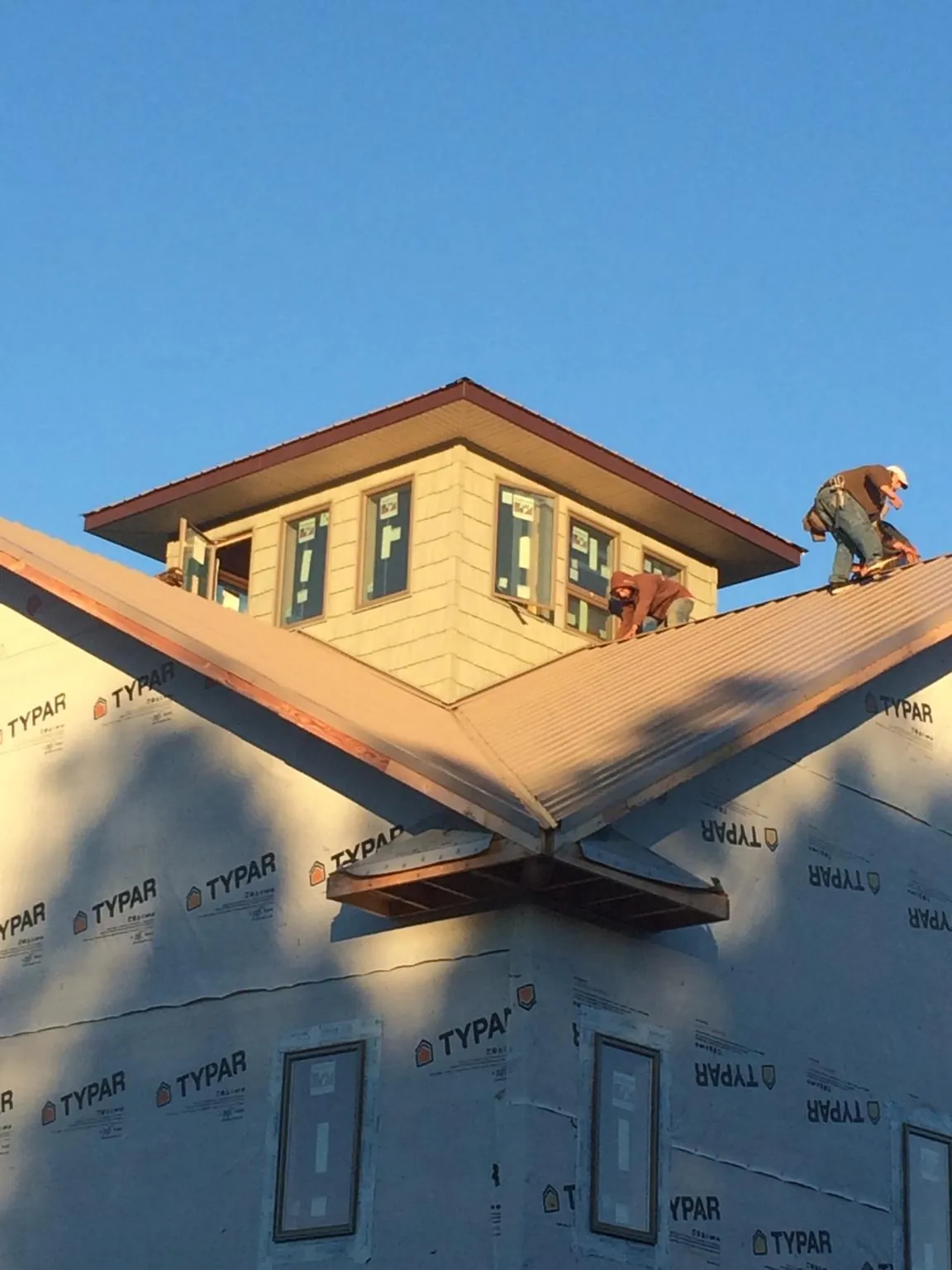 Roofers working around a rooftop cupola on a new metal roof at sunset — Roof Waterproofing in Summerfield by Roofing Brothers